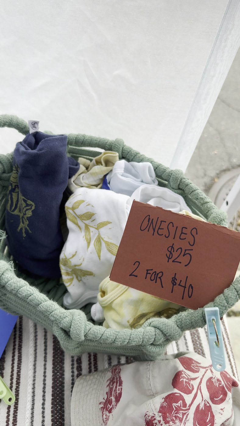 Basket of altered onesies with handmade price sign